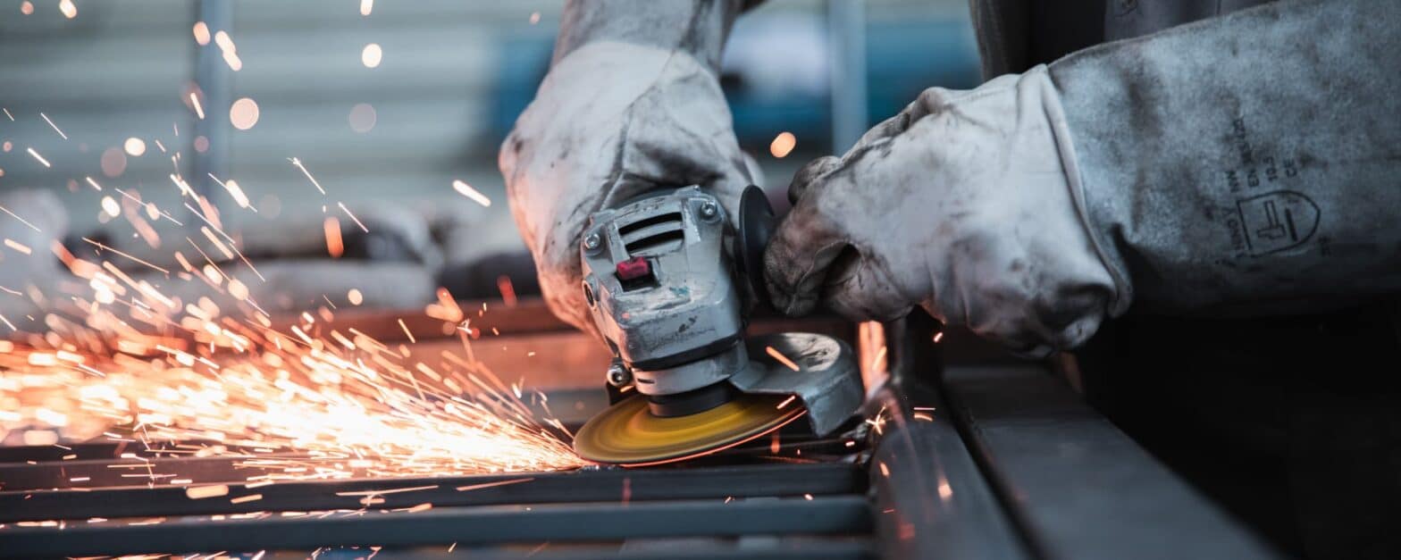 Photo of an individual working with a metal-cutting power tool.